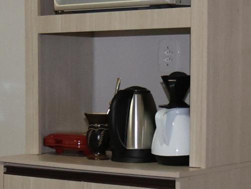 a shelf with a coffee pot and a tea kettle at Casa com estacionamento no centro de Concórdia SC in Concordia