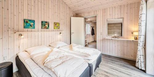 a large bed in a room with wooden walls at VE040-Vejers-Strand-Jafdalvej-5 in Vejers Strand