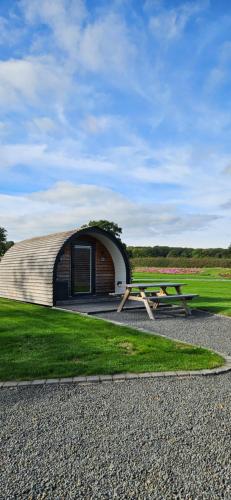 a building with a picnic table in front of it at Eastridge Glamping - Camping Pods in Shrewsbury