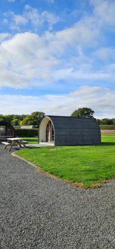 a black and white building with a bench in the grass at Eastridge Glamping - Camping Pods in Shrewsbury