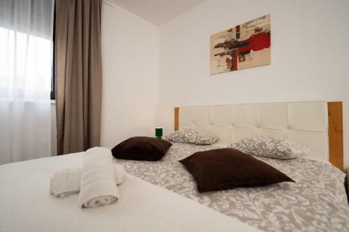 a white bed with two pillows on top of it at Secret Garden Apartman in Varaždin