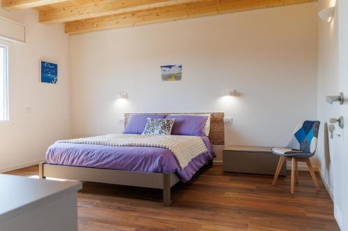 a bedroom with a bed with purple sheets and a chair at Il Sentiero di Arquà in Arquà Petrarca