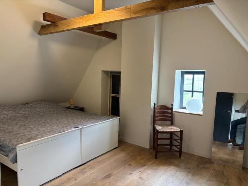 a bedroom with a bed and a chair and a window at Irene 2 in Hindeloopen
