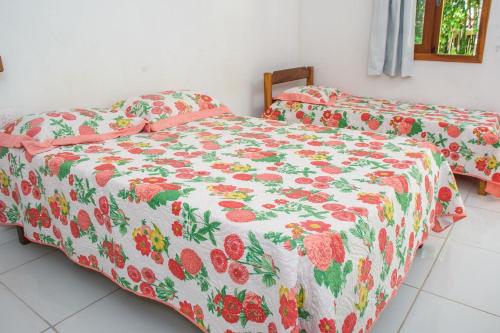 a bedroom with two beds with a floral bedspread at Chale 4 com Churrasqueira e Ar a 200m da Praia in Prado
