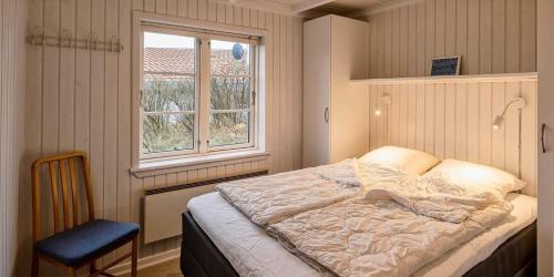 a bedroom with a bed and a window and a chair at VE147-Vejers-Strand-Violvej-16 in Vejers Strand