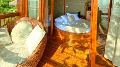 a porch with a bed and a chair on a deck at MAKAI BEACH HOSTEL in Punta de Piedra