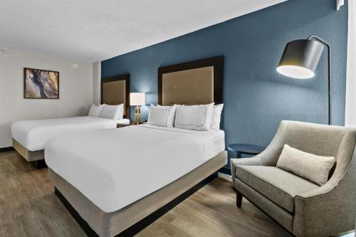 a hotel room with two beds and a chair at DoubleTree by Hilton Raleigh Midtown, NC in Raleigh