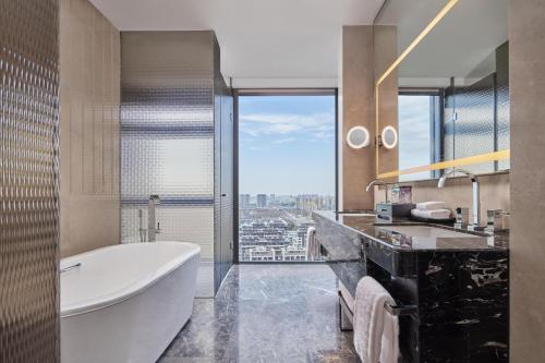 a bathroom with a tub and a large window at Hilton Yancheng in Yancheng