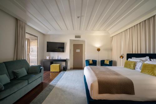 a hotel room with a bed and a couch at Convento do Seixo Boutique Hotel & Spa in Fundão