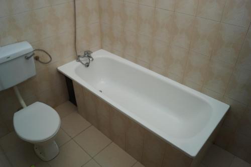 Durban Motel Najjanankumbi Kampala في كامبالا: حمام مع حوض استحمام أبيض ومرحاض