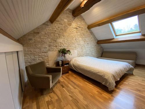 a bedroom with a bed and a chair at Le Verger de la Tannerie in Chesley