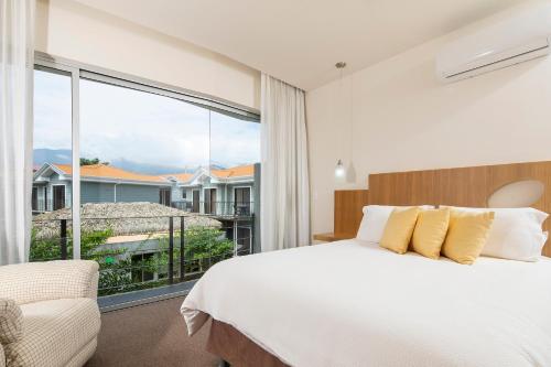 a bedroom with a bed and a large window at Hotel Villa Los Candiles in San José