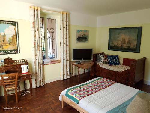 a bedroom with a bed and a desk and a television at Moulin de la Varenne in Saint-Saturnin