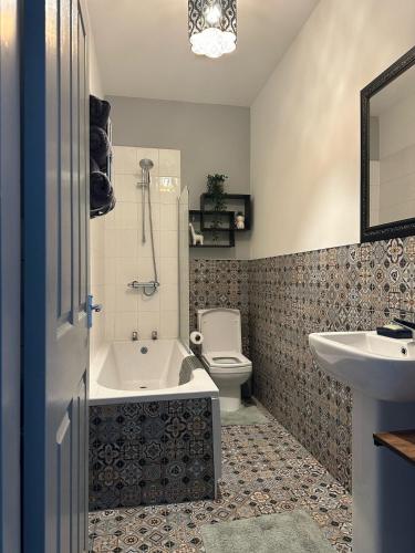 a bathroom with a tub and a toilet and a sink at Snuggle Inn Burnley in Burnley