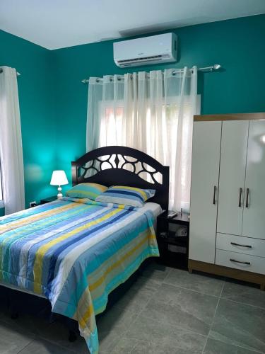a bedroom with a bed and a green wall at Blue Paradise in Coxen Hole