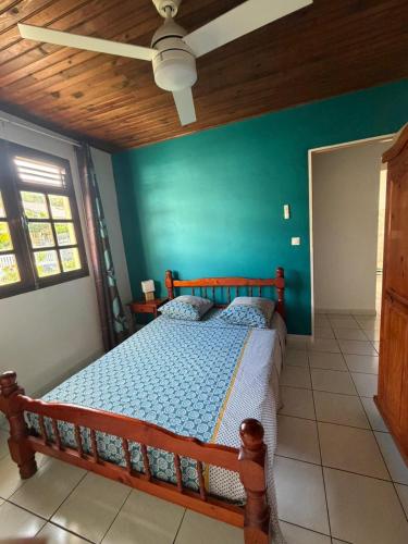 a bedroom with a wooden bed with a blue wall at Le Désircaraïbe in Tartane
