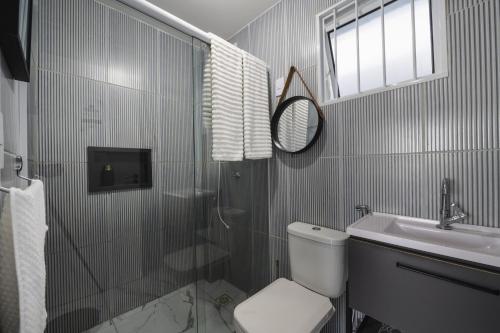 a bathroom with a shower and a toilet and a sink at Pequeno Paraíso Flats Praia Bela in Pitimbu