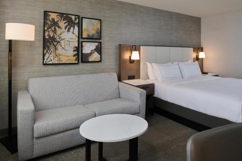 a hotel room with a bed and a couch and a chair at Doubletree by Hilton Buena Park in Buena Park