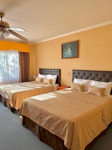 a hotel room with two beds and a ceiling fan at Hotel Econohotel in Los Ángeles