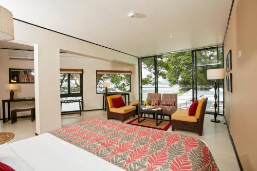 een slaapkamer met een bed, stoelen en ramen bij Ekho Safari Tissa in Tissamaharama