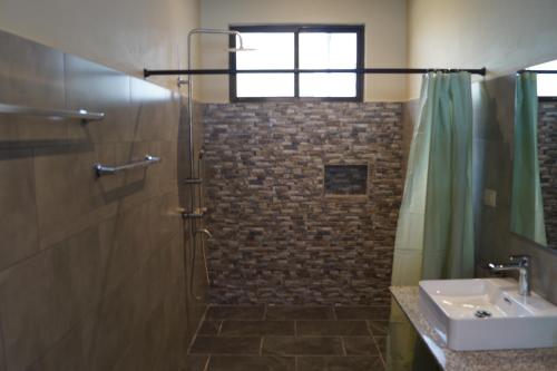 a bathroom with a shower and a sink at Finca Las Raíces Posada Rural in Zarcero
