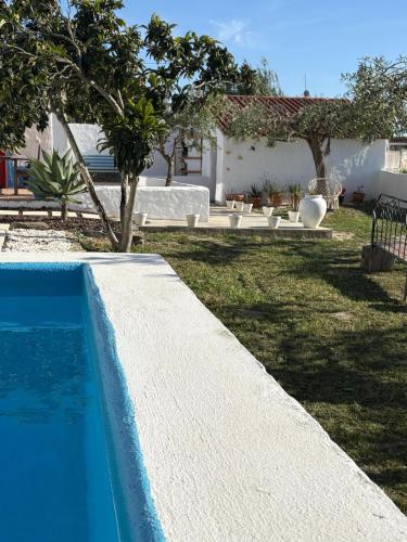 a swimming pool in a yard with two white benches at Canto da Planície in Conceição