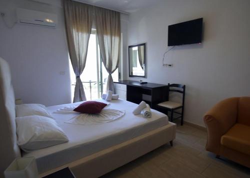 ein Schlafzimmer mit Bett, Schreibtisch und Fernseher in der Unterkunft Mare Blue Hotel Drymades in Dhërmi