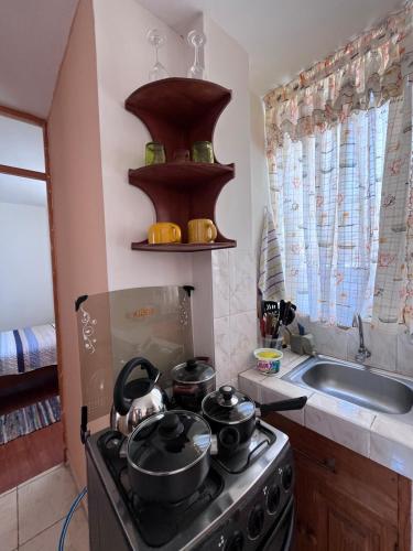 a kitchen with a stove with pots and pans on it at Minidpto Wayra Huanchaco in Huanchaco
