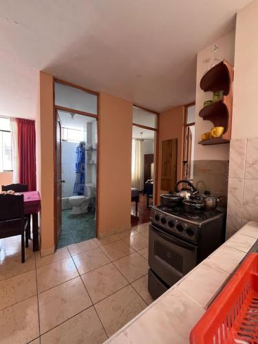 a kitchen with a stove and a living room at Minidpto Wayra Huanchaco in Huanchaco