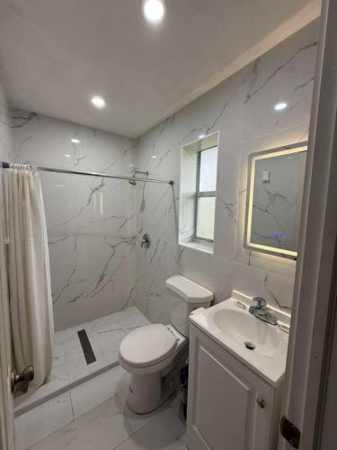 a white bathroom with a toilet and a sink at Conty's Motel in Naples
