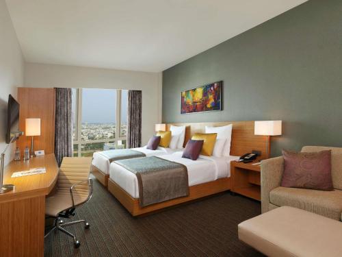 a hotel room with a large bed and a desk at Novotel Lucknow Gomti Nagar in Lucknow