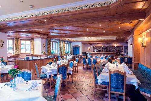 un comedor con mesas blancas y sillas azules en Hotel Restaurant Stöcklwirt en Sankt Johann im Pongau