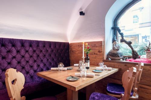a dining room with a wooden table and purple booths at Hotel Restaurant Stöcklwirt in Sankt Johann im Pongau