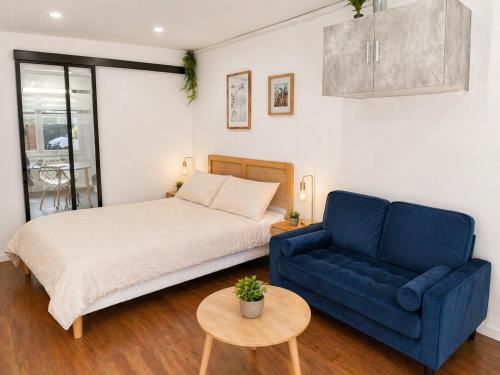 a bedroom with a bed and a blue couch at Appartement 4 ou 2 Parking Wifi Terrasse cosy in Condé-sur-Sarthe