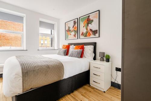 a bedroom with a large bed and two windows at Luxury Apartment Close to Elstree & Borehamwood Station in Borehamwood