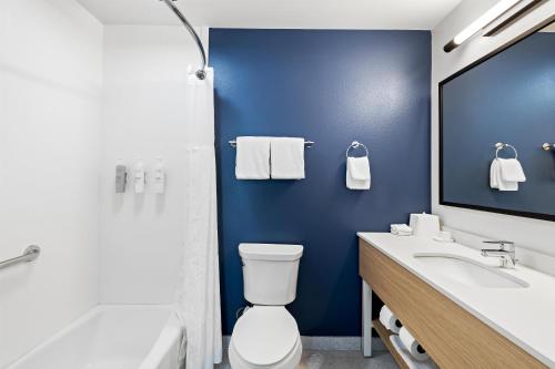 a bathroom with a white toilet and a blue wall at Spark By Hilton Redlands in Redlands