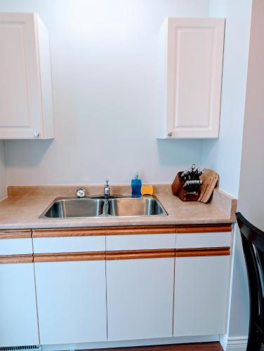 a kitchen with a sink and white cabinets at Executive Suite 2 Bedroom Serviced Apartment in Alert Bay