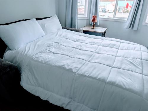 a large white bed in a bedroom with a window at Executive Suite 2 Bedroom Serviced Apartment in Alert Bay