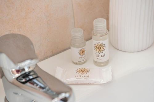 two bottles of natural products sitting on a bathroom counter at Hedoné apartment in Schisò