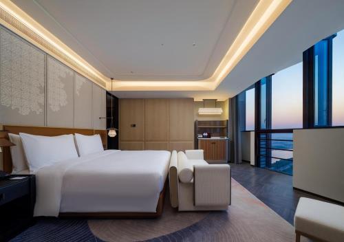 a bedroom with a large white bed and large windows at DoubleTree by Hilton Zhangzhou in Zhangzhou