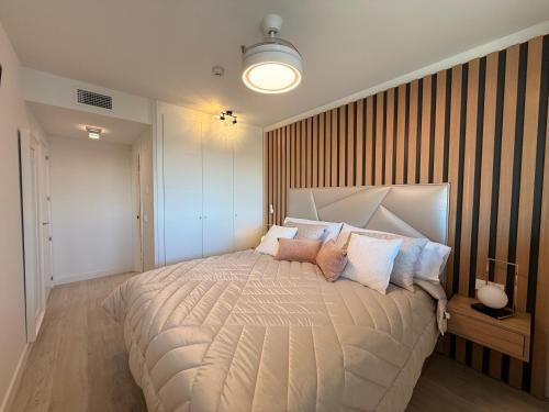 a bedroom with a large bed with a striped wall at Apartamento Blois Deluxe in Rivas-Vaciamadrid
