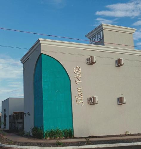 a building with a green door and the words hotel at Slan Ville Hotel in Chapadão do Sul