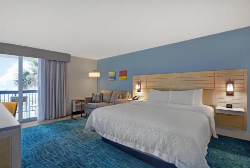 a hotel room with a bed and a balcony at Hampton Inn Oceanfront Jacksonville Beach in Jacksonville Beach