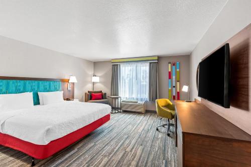 a hotel room with a bed and a flat screen tv at Hampton Inn & Suites Lathrop in Lathrop