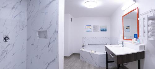 two images of a bathroom with a sink and a mirror at Hampton Inn & Suites Seal Beach in Seal Beach