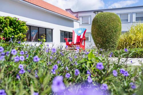 a red chair and purple flowers in front of a house at Spark by Hilton Ponce in Ponce