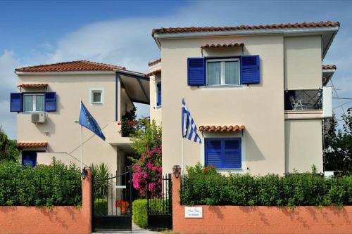 リジアにあるAnesis Village Studios and Apartmentsの青いシャッターと旗が目の前にある建物