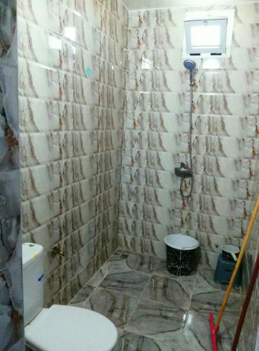 a bathroom with a toilet and a stone wall at Classico Apartments in Tan-Tan Plage