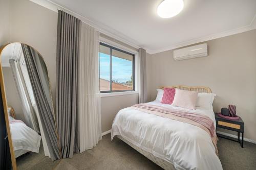 a small bedroom with a bed and a window at Pacific Palms Retreat - Entire Home in Plumpton Sleeps 9 - 8-Car Parking Near Eastern Creek in Rooty Hill