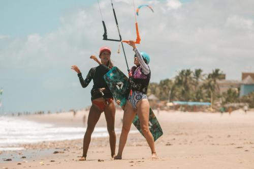 two women standing on the beach holding onto a kite at Controvento Boutique Hotel - Yoga Kitesurf in Cumbuco